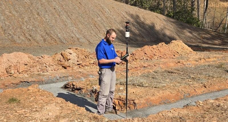 Field survey in progress showing a surveyor working with an AutoPole and prism on a survey pole during a house staking project.